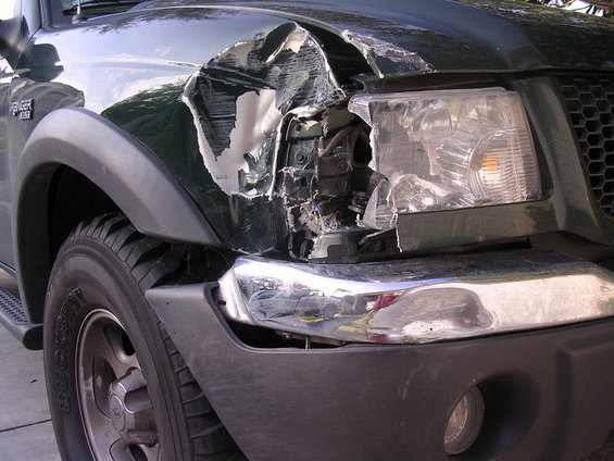 Damaged dark green truck front fender and headlight