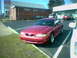 1996 Ford Mustang - A red 1996 Ford Mustang coupe is parked in a lot on a sunny day.