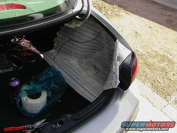 Silver sedan trunk interior with a roll of tape, spray can, and tools