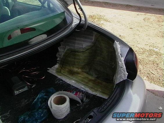 Trunk interior with fiberglass matting and supplies. Rear view