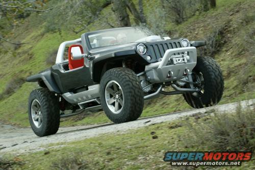 Custom off-road vehicle with large tires and red interior driving on a dirt road