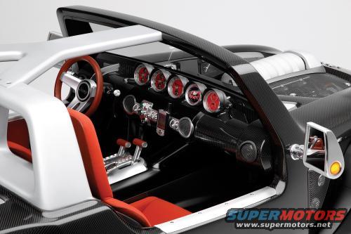 Car interior with red seats, chrome shifter, and red-faced gauges. Carbon fiber accents visible