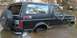 1988 Ford Bronco - A black Ford Bronco is stuck in shallow water, with its tires submerged and water splashing.
