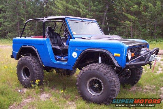 Blue 1974 Ford Bronco modified for off-roading with large tires and a roll cage