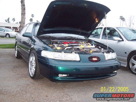 Green sedan with hood open, showing engine. Front view. Aftermarket wheels. Date stamp 01/22/2005