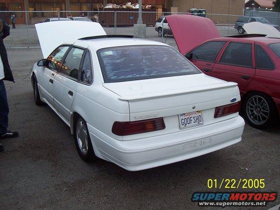 White Ford Taurus SHO with hood up, parked next to red car