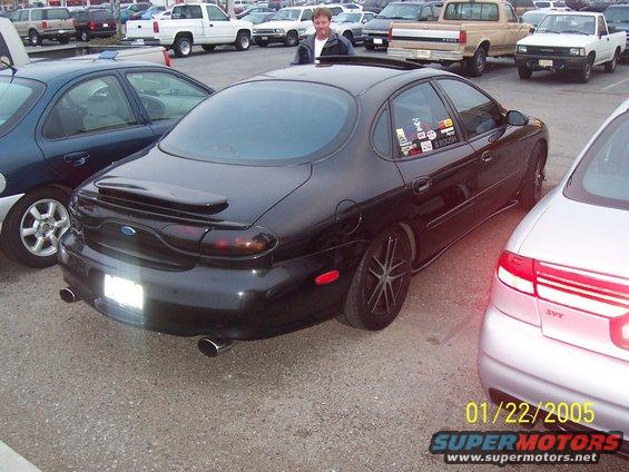 1998 Mercury Sable rear view, black paint, custom wheels, parked next to silver car