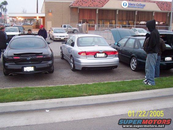 Black Ford Taurus parked next to a silver sedan and a dark green sedan