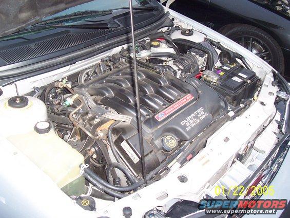 Engine bay with Duratec 2.5L V6 24 Valve DOHC engine cover visible. Another car is parked behind