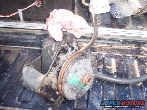 Power steering pump with pulley and hose, resting in a truck bed