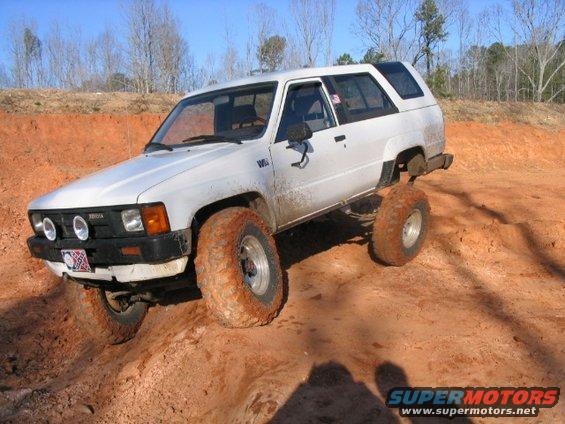 White Toyota 4Runner with mud-covered tires on a dirt trail