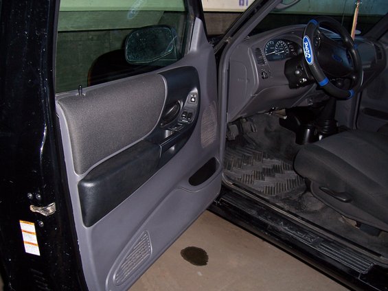 2003 Ford Ranger interior showing door panel, dashboard, steering wheel, and floor mats