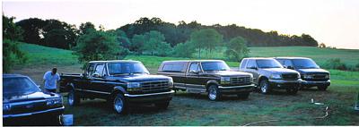 Several trucks and SUVs parked in a field at dusk