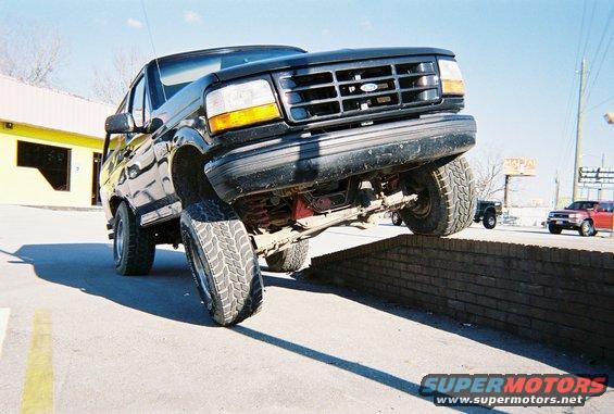 Black Ford Bronco with front passenger tire on a brick wall