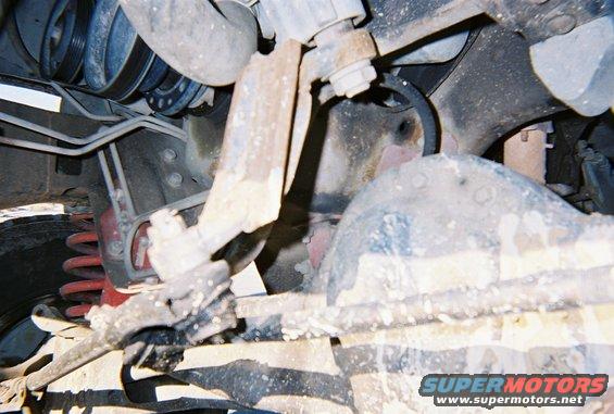 Close-up of rusty suspension parts, hoses, and engine components under a vehicle