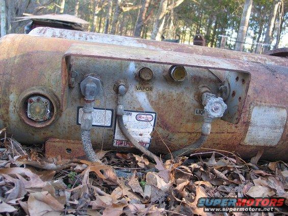 rusty propane tank with vapor and liquid valves, and a warning label