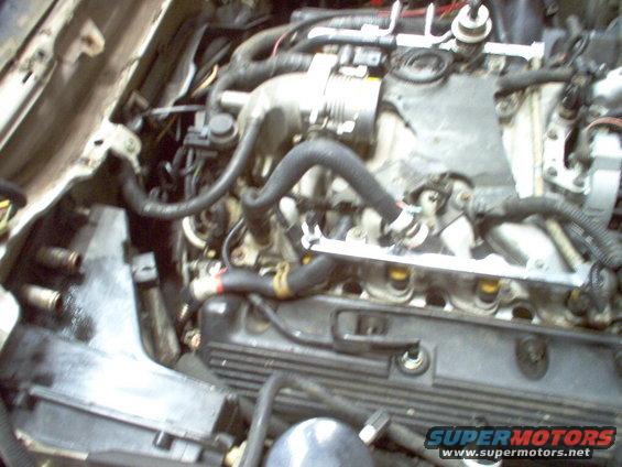 Engine bay with hoses and wiring visible, some parts removed