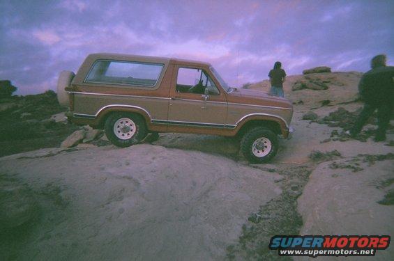 1983 Ford Bronco parked on rocky terrain under a purple sky
