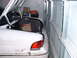 1996 Ford Crown Victoria - The trunk of a white car is open, revealing a box of drinks and other items, as it is parked tightly in a garage.