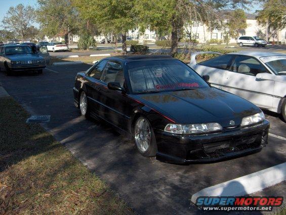 1990 Acura Integra coupe, black with red pinstripe, parked next to a white car