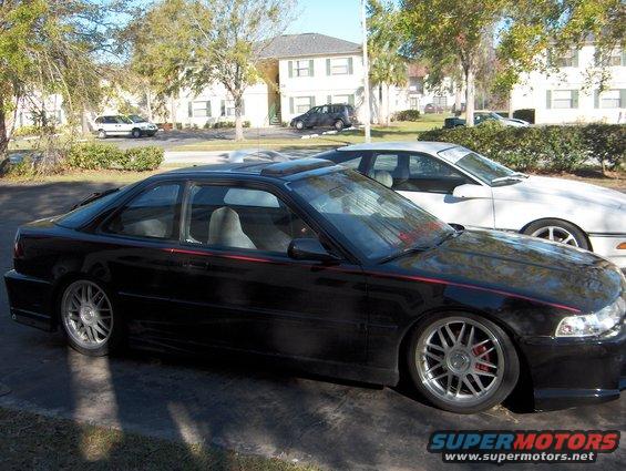 black coupe with red stripe, parked next to white car