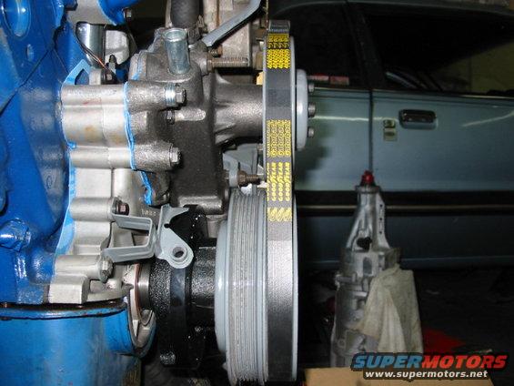 Close-up of engine components and a transmission with a light blue car door in the background