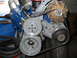1985 Ford Crown Victoria LTD - This image shows a collection of engine components, including pulleys and belts, against a blue engine block.