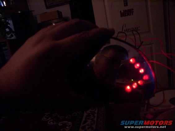 Hand holding a mirror with red LEDs arranged in a turn signal pattern