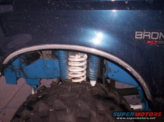 1993 Ford Bronco rear suspension with blue shocks and white coil springs, showing part of the tire