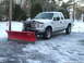 2000 Ford F-250 - A white Ford F-250 truck equipped with a snow plow is parked on a snow-covered surface.