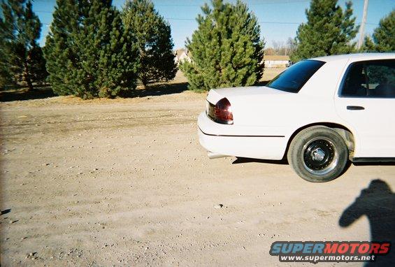 White 2000 Ford Crown Victoria parked on dirt lot with trees behind it