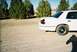 2000 Ford Crown Victoria - Rear view of a white 2000 Ford Crown Victoria parked outdoors on a dirt surface.