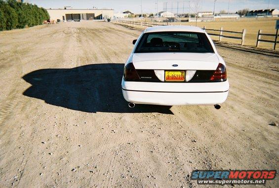 White 2000 Ford Crown Victoria rear view, parked on dirt road