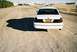 2000 Ford Crown Victoria - Rear view of a white 2000 Ford Crown Victoria on a dirt road with a building in the background.