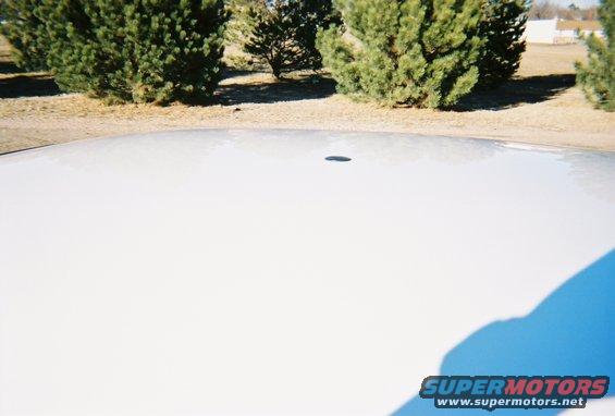 White car roof with a small dark antenna base and a shadow on the right