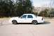 2000 Ford Crown Victoria - A white 2000 Ford Crown Victoria is parked on the side of a road, with trees and a fence visible behind it.