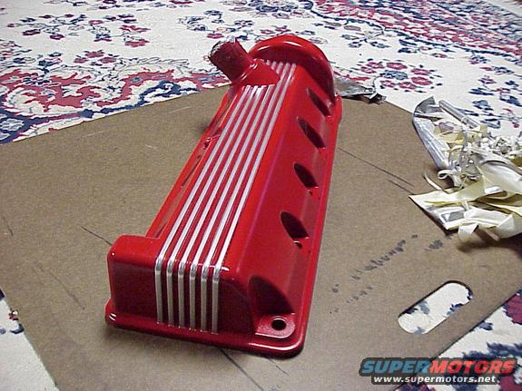 Red engine valve cover with silver stripes, sitting on cardboard