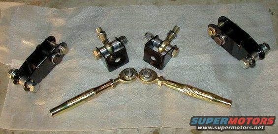 Four black and gold automotive suspension components laid out on a textured surface