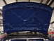 1998 Volkswagen Jetta - The underside of a blue car hood is shown, revealing its internal structure and reinforcement beams.