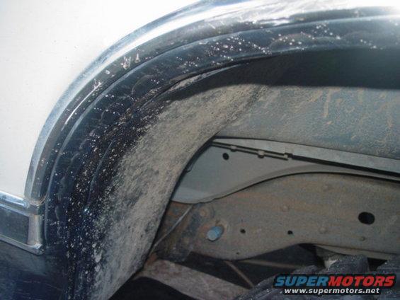 Close-up of a dirty wheel well and suspension parts, showing mud and grime