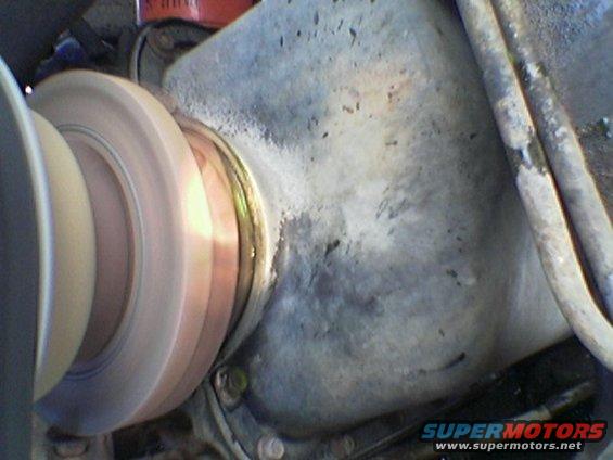 Close-up of a spinning pulley and a gray engine component, possibly a water pump housing