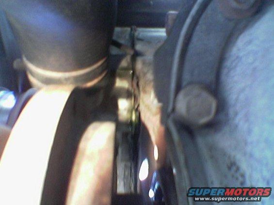 Close-up of a metal pulley and hose clamp, part of an engine