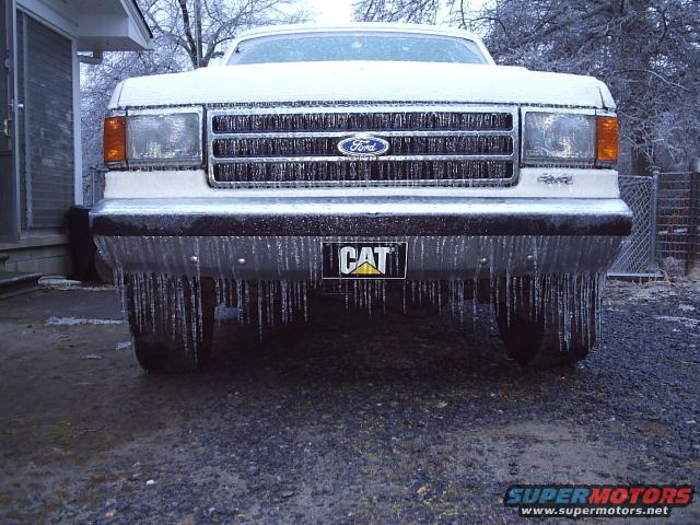 White 1989 Ford Bronco front view covered in ice with CAT logo on bumper