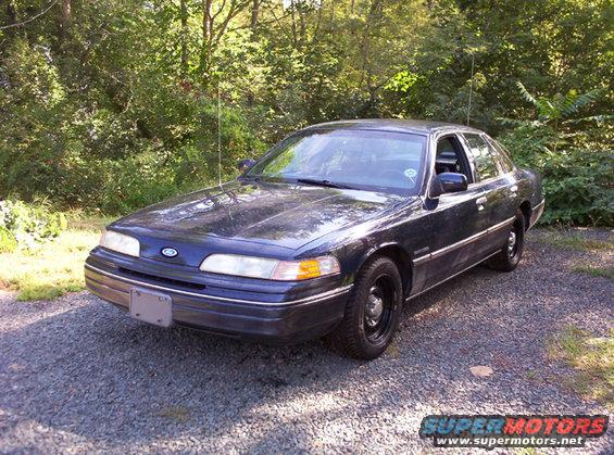 Dark blue 1991 Ford Crown Victoria parked on gravel, trees in background