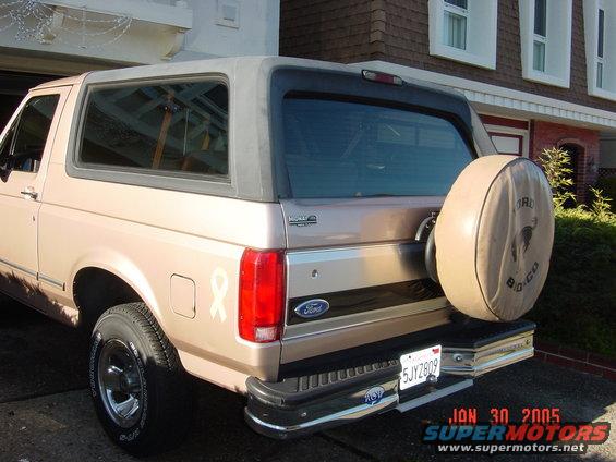 1990 Ford Bronco rear view, tan color, with spare tire cover showing Bronco logo