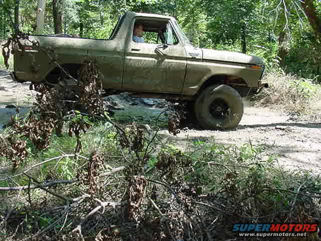 Olive green 1970s pickup truck off-road, side view