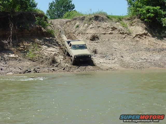 1978 Ford Bronco climbing a steep dirt bank near water