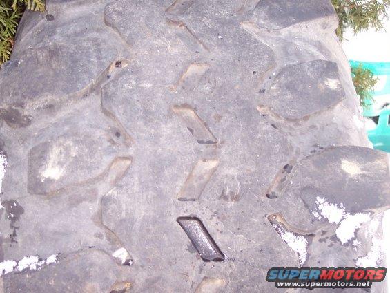close-up of a large, knobby tire tread with some snow on it