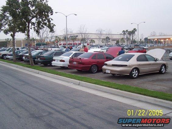 Gold sedan with hood open, parked in a lot with other cars