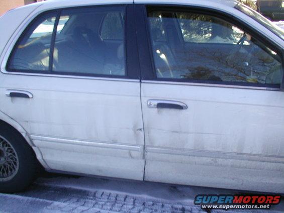 White sedan side view with dent on rear door